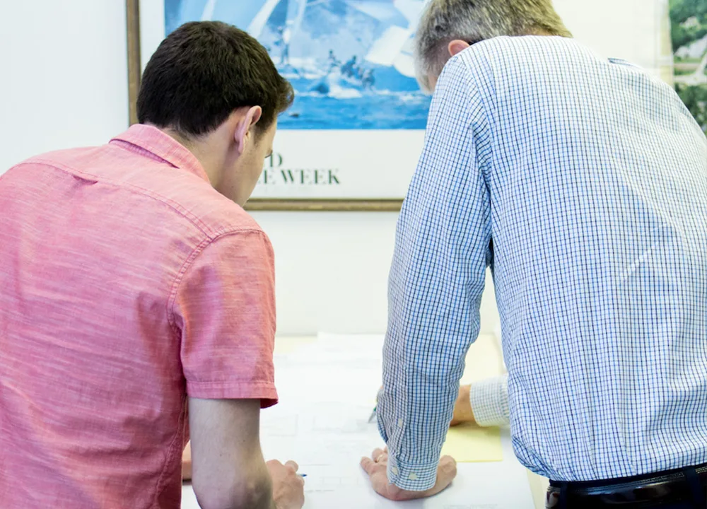 Employee mentoring another employee drawing on blueprints